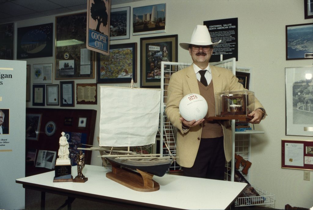Mayor Mike Harcourt posing in a cowboy hat in front of a display of some of Vancouver’s Centennial gifts. Reference code AM1576-S6-12-F49-: 2011-010.2027