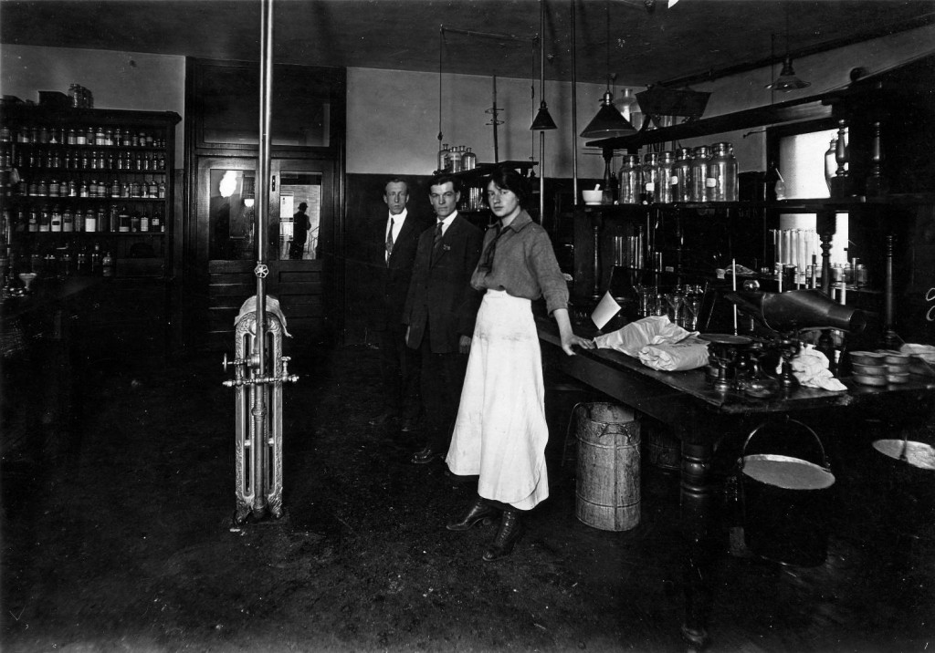 Pictured here are three of the BC Sugar laboratory staff members in 1916: Maggie McKenzie, Ernie Abbott, and R.B. This photograph was taken on second floor office building at BC sugar. Reference code: 2011-092.1854.