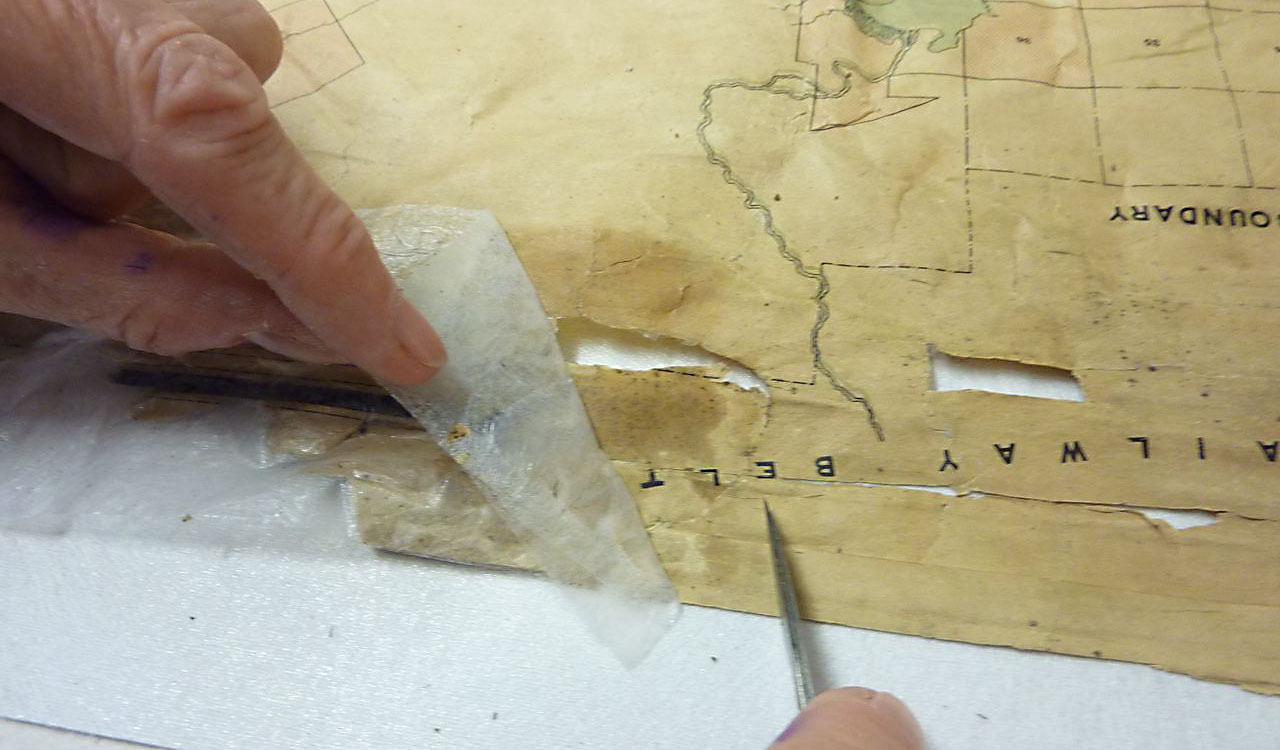 Peeling a piece of fabric from the face of the map