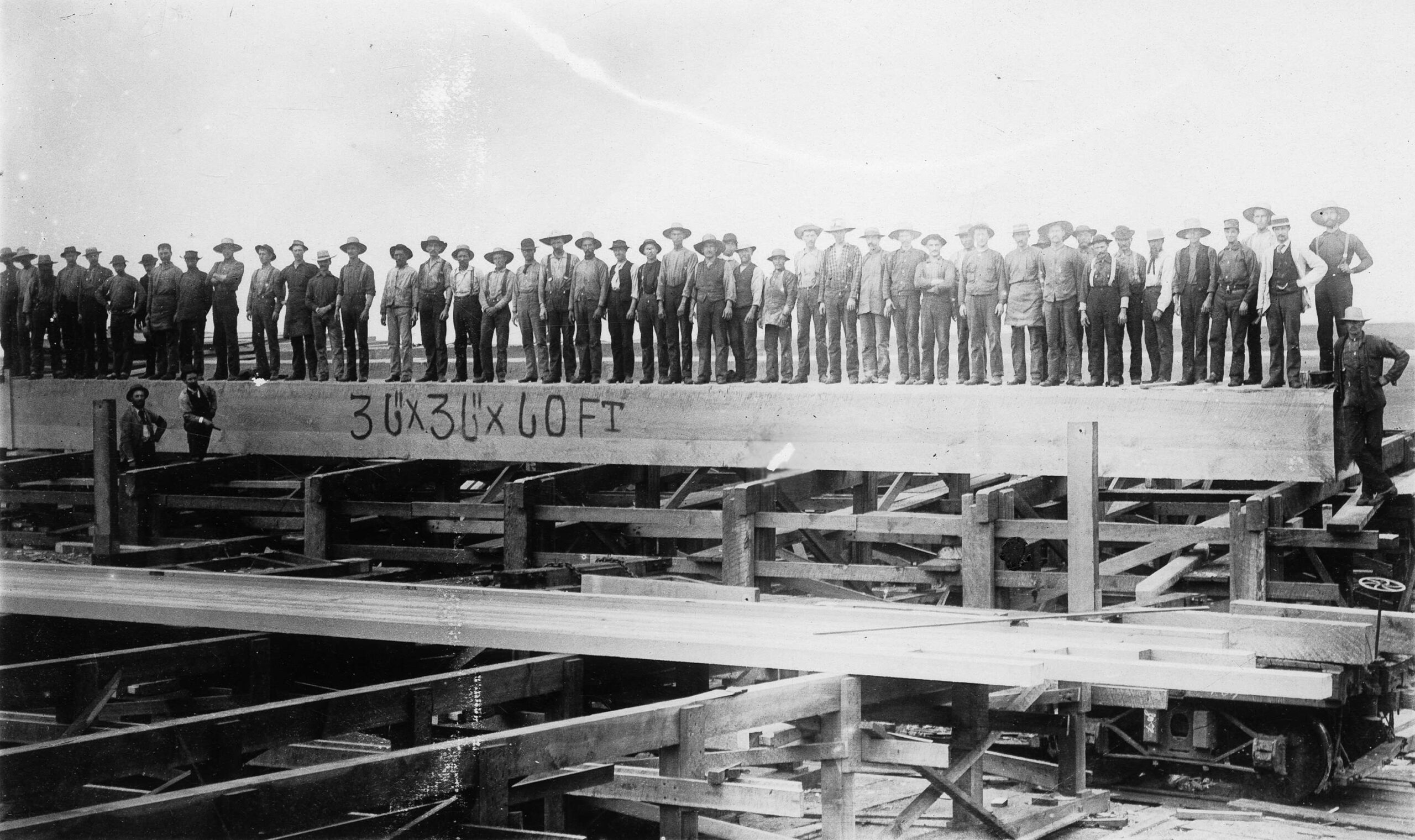 Hastings Sawmill workers lined up along a 60 foot long beam, 1900. Reference code: AM1036-S4-: CVA 703-4.7.5