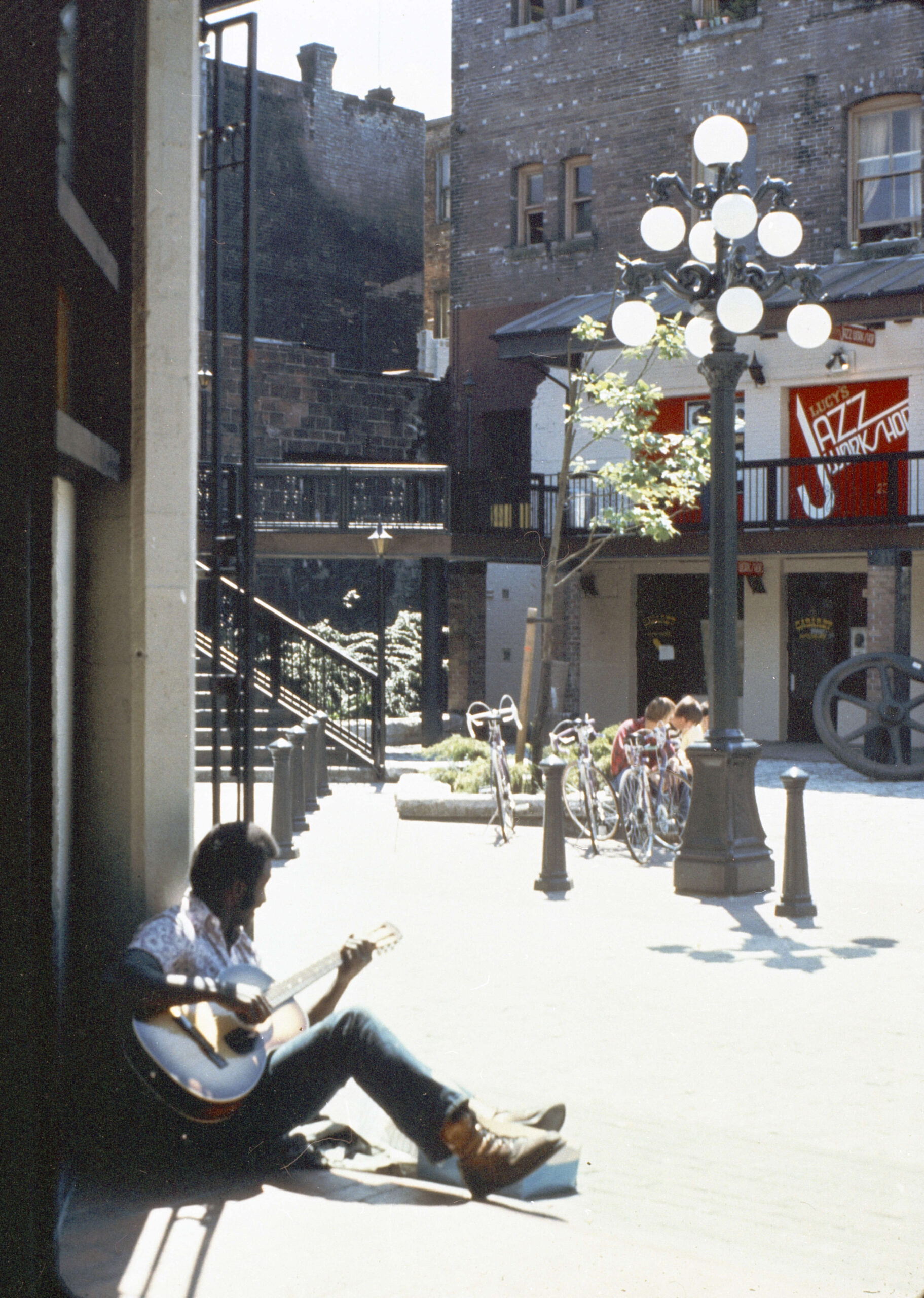 Man playing guitar in Blood Alley Square. Reference code: COV-S644-: CVA 1095-13344