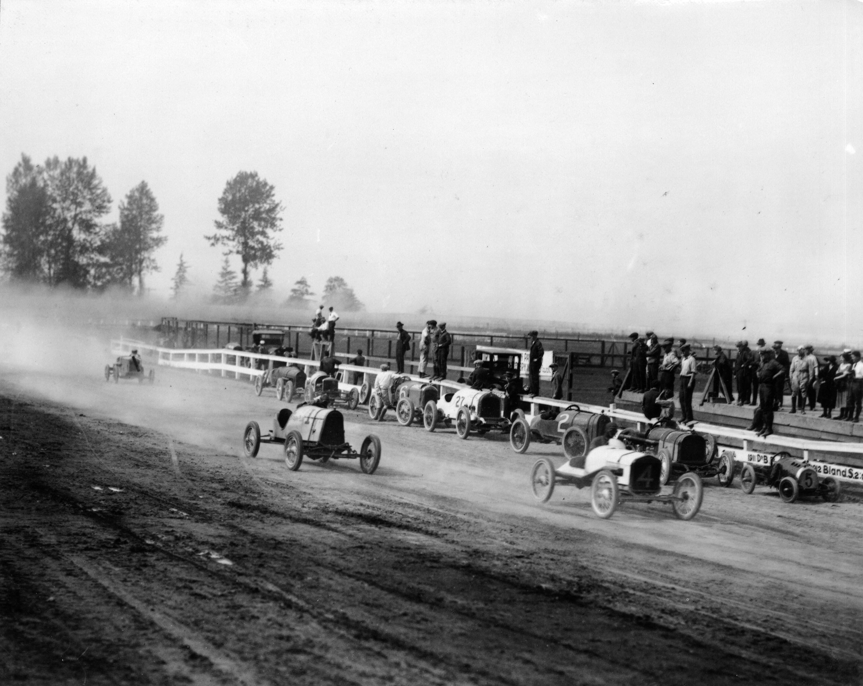 cars on track, with spectators nearby