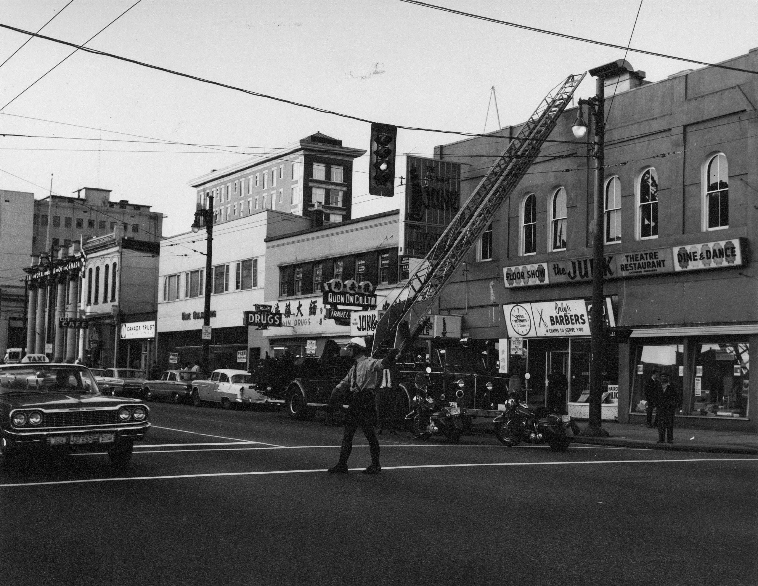 Directing traffic with a fire engine attending a building at Pender and Main, 1967. Reference code: VPD-S214-: CVA 490-273