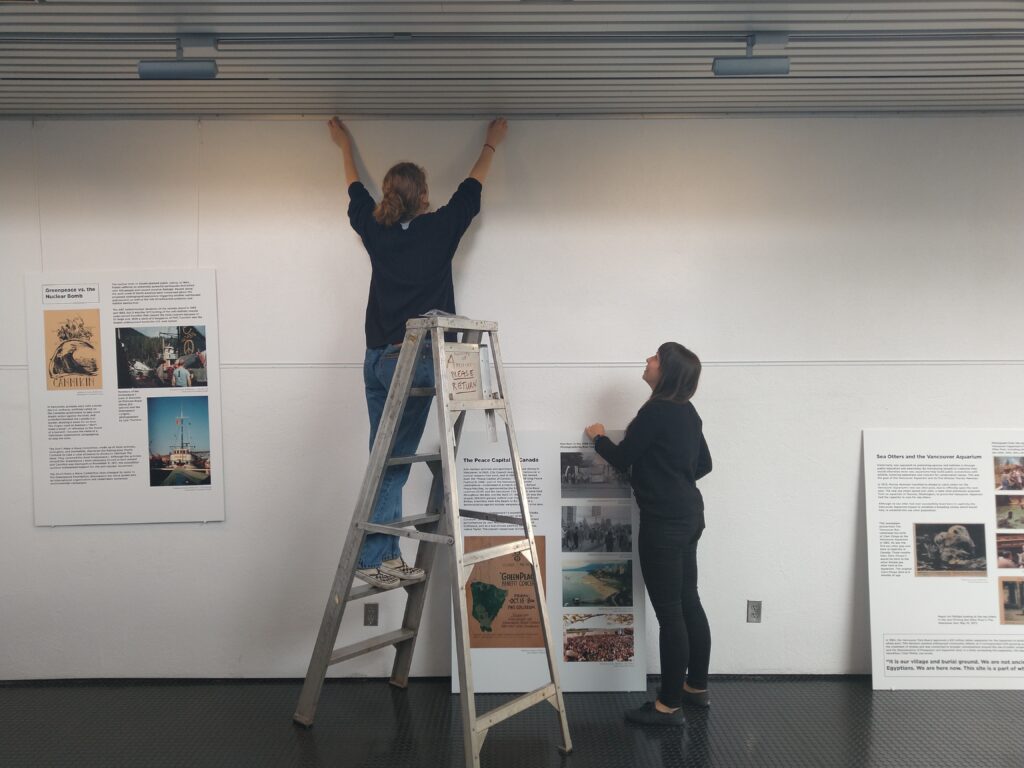 Camryn and Mandy Roddick, the City of Vancouver Archives’ Digitization Assistant, hanging the exhibit panels. Photo by Kira Baker.